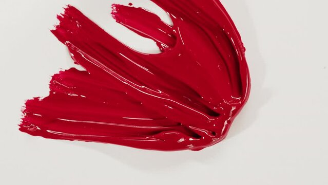 Mixing red paint close-up. Drawing on white paper top view. Smearing guache using paintbrush. Hobby and art concept.
