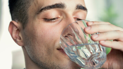 Young man drinks a glass of water