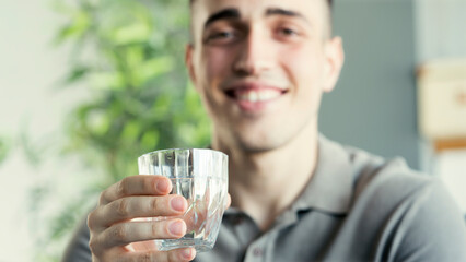Young man drinks a glass of water	