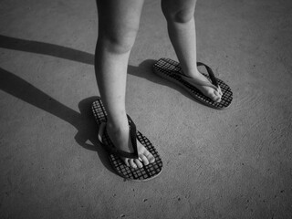kids feet in adults black flip flops