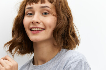 a happy, very joyful woman stands on a white background in a gray T-shirt smiling broadly expressing her emotions. Close horizontal photo