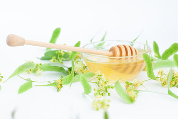 Natural linden honey with linden flowers on a white background