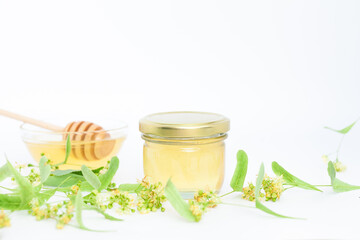 Natural linden honey with linden flowers on a white background