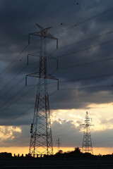 Duże słupy energetyczne z elektrowni dostarczają prąd do miasta - obrazy, fototapety, plakaty