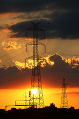 Duże słupy energetyczne z elektrowni dostarczają prąd do miasta - obrazy, fototapety, plakaty