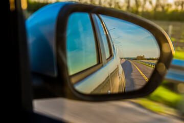The road is reflected in the side mirror of the car