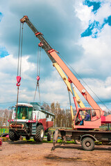 Two cranes lift the harvester. Loading of heavy equipment