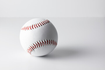 White baseball with red threads on a light surface