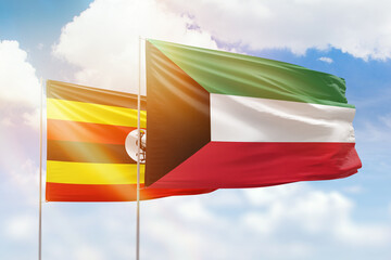 Sunny blue sky and flags of kuwait and uganda