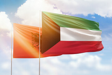 Sunny blue sky and flags of kuwait and albania