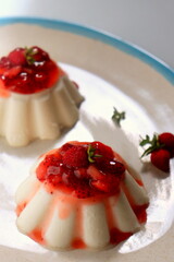 a sweet dessert of cream jelly with a berry confiture of strawberries close-up on a plate.