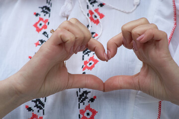 Ukrainian woman makes a heart with her hands. girl in an embroidered jacket, national costume. stop war.
