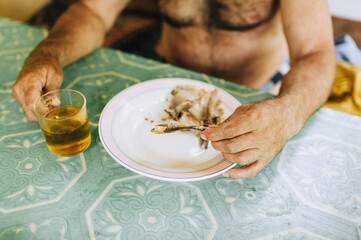 Adult Russian man drinks beer and eats dry fish while sitting in a bar in summer. Alcoholism in Russia.