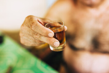A man holds a glass of vodka, brandy in his hands close-up. Food photography.