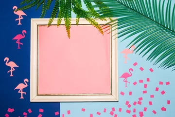Fotobehang old white retro frame with pink copy space, around the frame flamingo jungle leaves and confetti on a dark and pastel blue background, creative summer trendy design © Stefan
