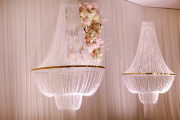 festive wedding decoration with crystal chandeliers and white pink flowers . stylish wedding day