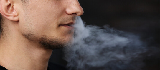 close up of a man with an electronic cigarette. man smokes an electronic cigarette in a natural...