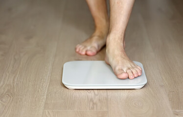 Man walking on scales measure weight. male wal checking BMI weight loss. human barefoot measuring body fat overweight. Guy legs step on bathroom scale