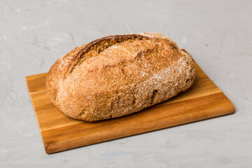 Freshly baked bread on cutting board against white wooden background. perspective view bread with copy space