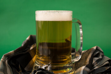 Glass of cold beer on green background