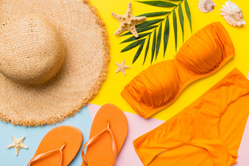 Woman swimwear and beach accessories flat lay top view on colored background Summer travel concept. bikini swimsuit, straw hat and seasheels. Copy space Top view