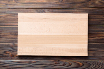 Top view of wooden cutting board on wooden background. Empty space for your design.=
