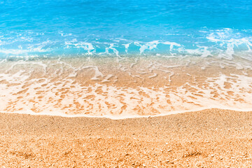 Fototapeta na wymiar Wallpaper of turquoise blue clear foamy sea and sandy beach in a sunny summer day