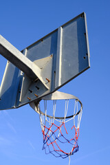 Basketball hoop and net against a blue sky. Urban youth game. Low angle view below the hoop net....