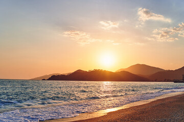 Landscape of beautiful idyllic sunset sky, sea, sandy beach and mountains