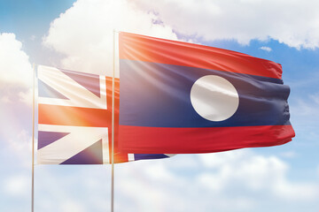 Sunny blue sky and flags of laos and great britain