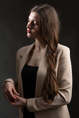 Portrait of a young brunette with long hair in the studio. Dramatic photo in dark colors.