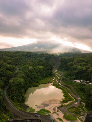 The view of Mount Merapi with the Bebeng River and a lake that holds water, the sky looks cloudy. Forest vegetation that looks still dense with trees surrounding the lake. Bego Pendem, Mount Merapi