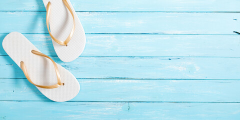 White flip-flops on color wooden background. Vacation concept. Flat lay, top view, copy space