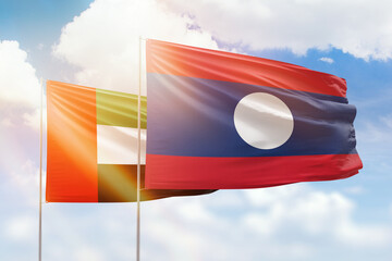 Sunny blue sky and flags of laos and uae
