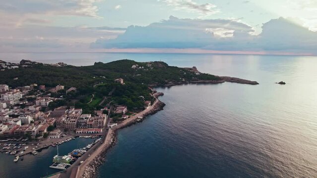 Panoramic view of a Spanish Town Port Cala Rajada with turquoise sea at sunset. Es Pelats and Cala Ratjada city from above in Majorca, Balearic Islands, Spain, drone view.