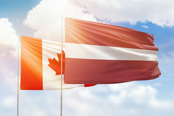 Sunny blue sky and flags of latvia and canada