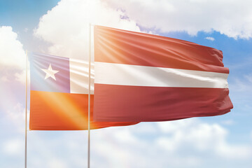 Sunny blue sky and flags of latvia and chile