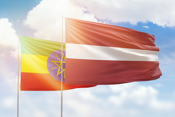 Sunny blue sky and flags of latvia and ethiopia