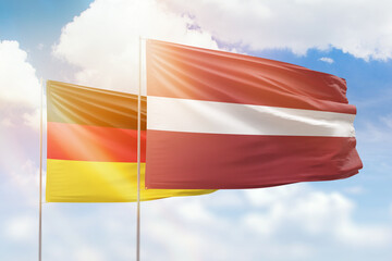 Sunny blue sky and flags of latvia and germany