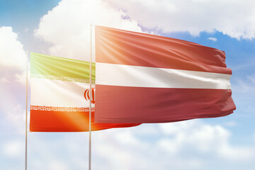Sunny blue sky and flags of latvia and iran