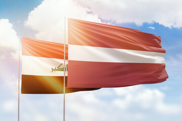 Sunny blue sky and flags of latvia and iraq