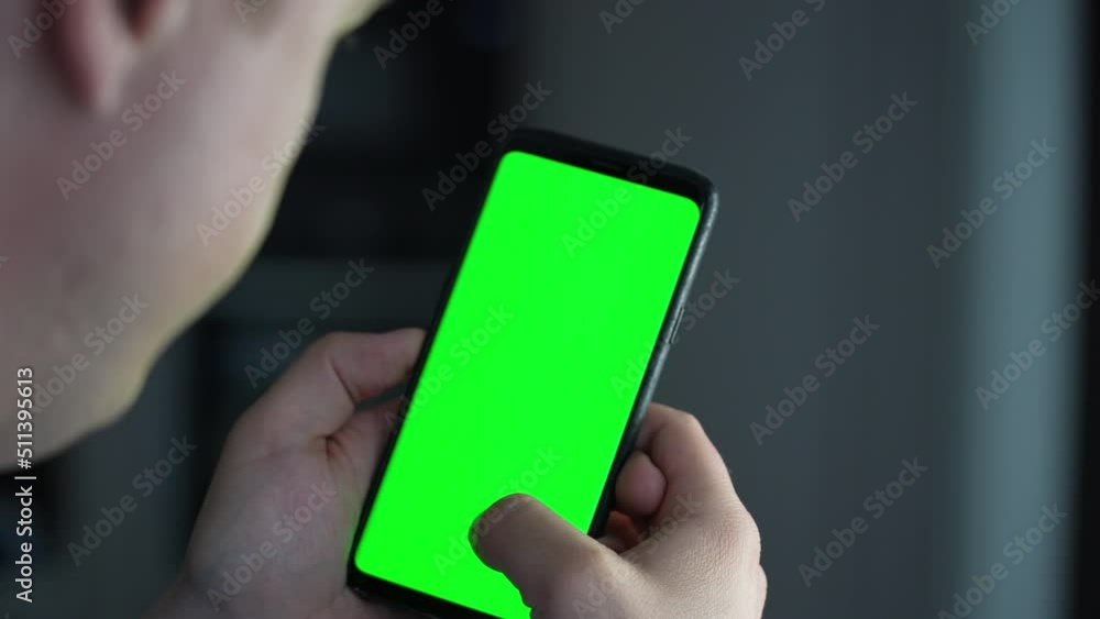 Poster close-up of male hands touching of smartphone. man holds mobile phone in hand with green chromakey s
