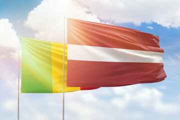Sunny blue sky and flags of latvia and mali