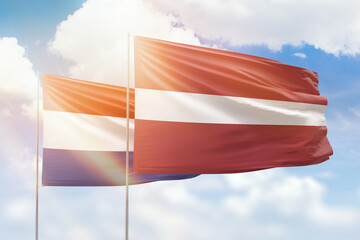 Sunny blue sky and flags of latvia and netherlands