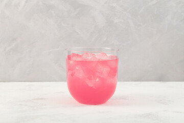 Delicious lychee cocktail with ice cubes in clear glass on gray background. Refreshing summer iced...