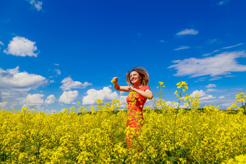 Young pretty woman in a colored dress on Lightning cheerful yellow background blooming rapeseed...
