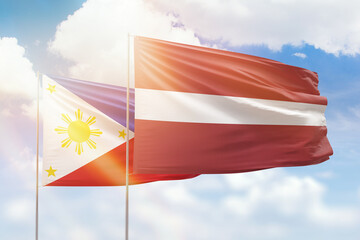 Sunny blue sky and flags of latvia and philippines