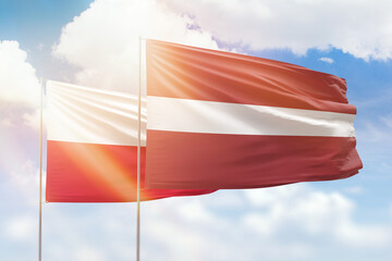 Sunny blue sky and flags of latvia and poland