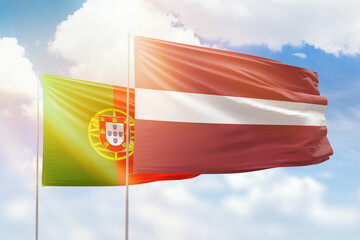 Sunny blue sky and flags of latvia and portugal