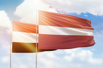 Sunny blue sky and flags of latvia and yemen